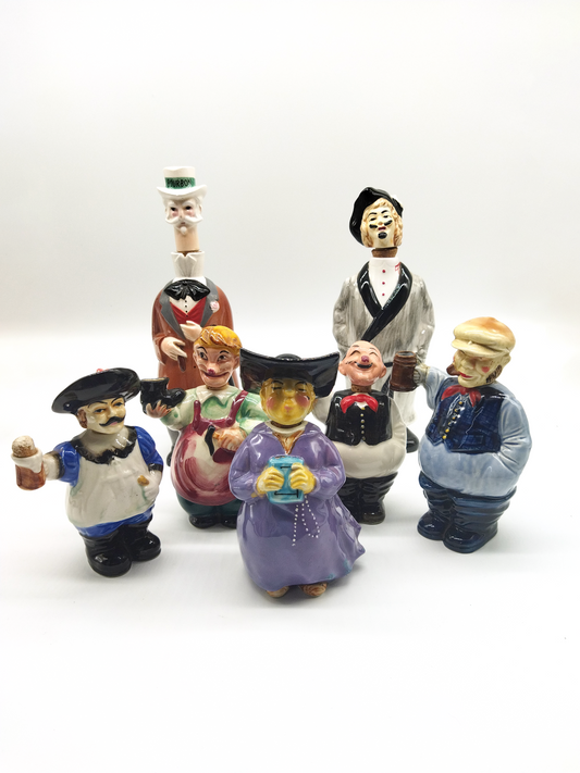 A COLLECTION OF SEVEN HAND PAINTED NOVELTY DECANTERS CIRCA 1960.