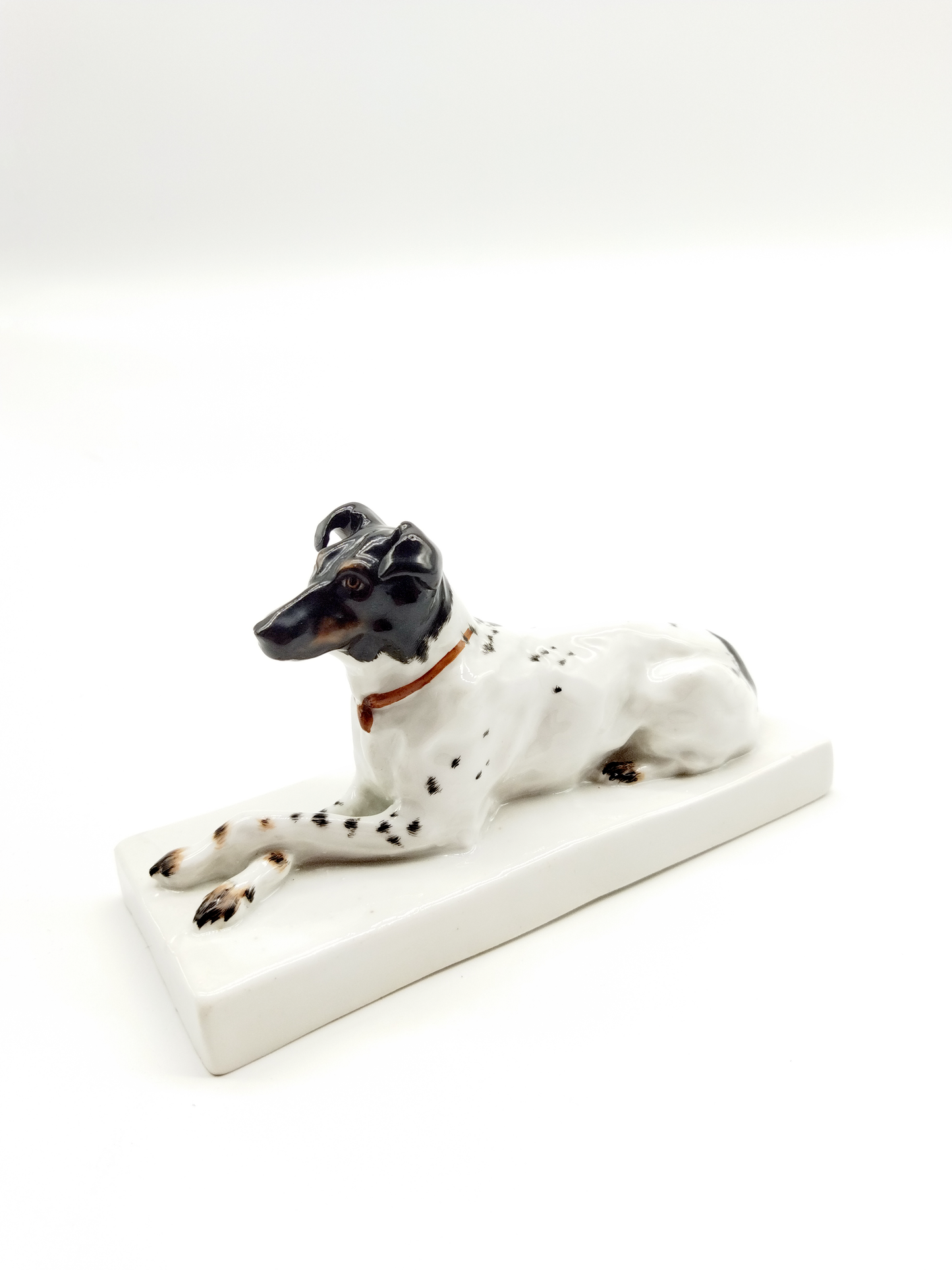 A GERMAN BLANC-DE-CHINE RECLINING DOG PORCELAIN FIGURINE