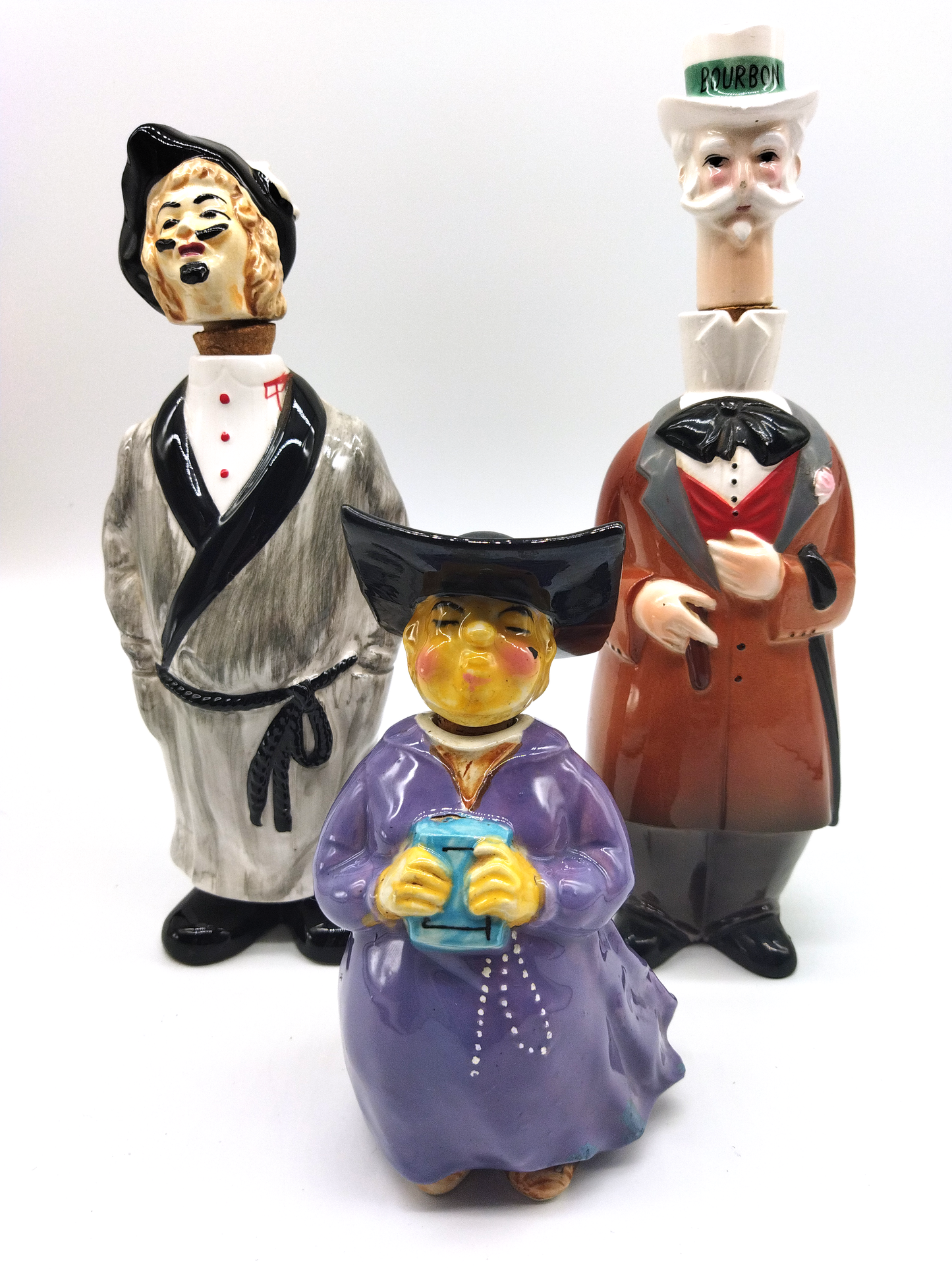 A COLLECTION OF SEVEN HAND PAINTED NOVELTY DECANTERS CIRCA 1960.