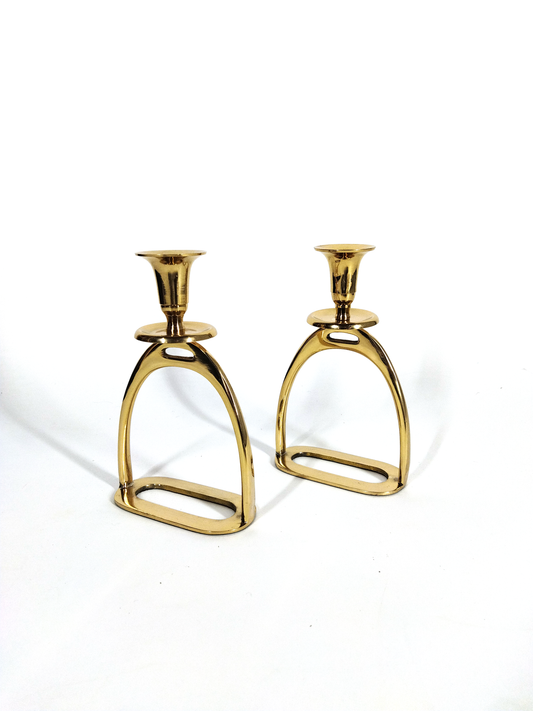 A PAIR OF HORSE STIRRUP CANDLE HOLDERS IN GOLD TONE METAL.