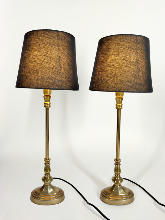 A PAIR OF OVAL ANTIQUE GOLD TABLE LAMPS WITH BLACK TAPERED SHADES.